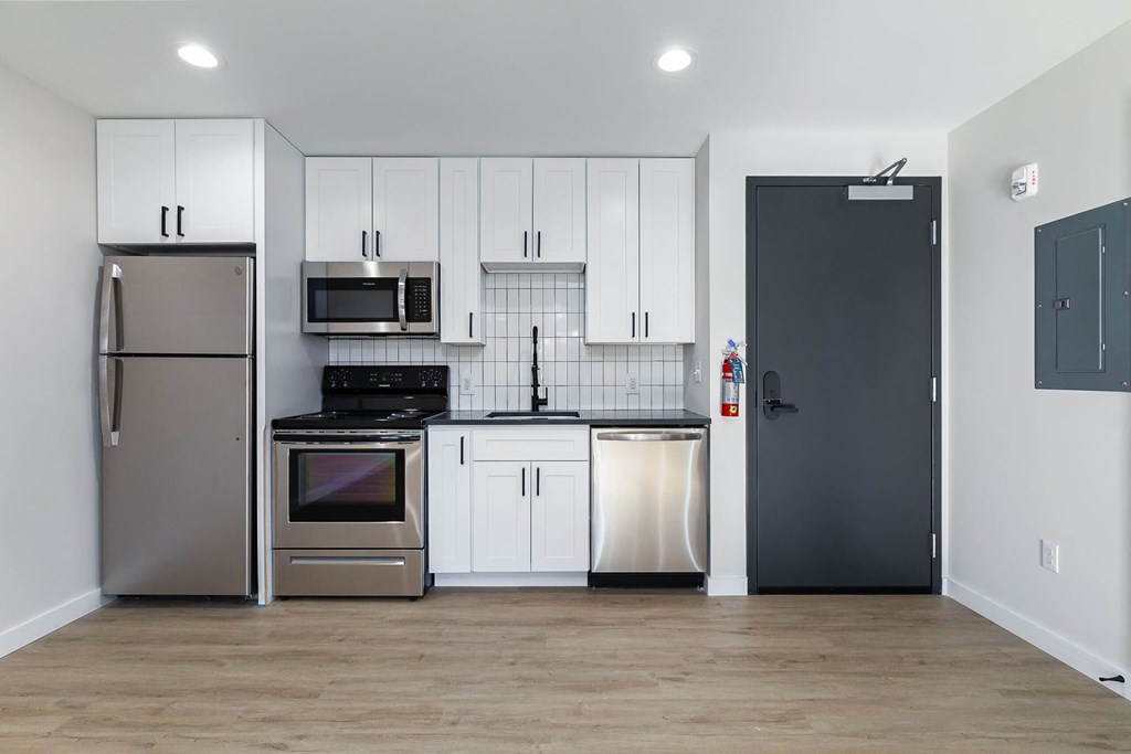 A kitchen with a refrigerator, microwave, oven, dishwasher, and cabinets.