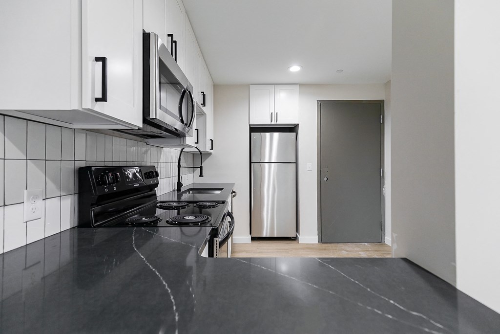 A kitchen with black countertops and stainless steel appliances.