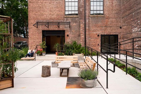 A courtyard with a bench, a table and a planter.
