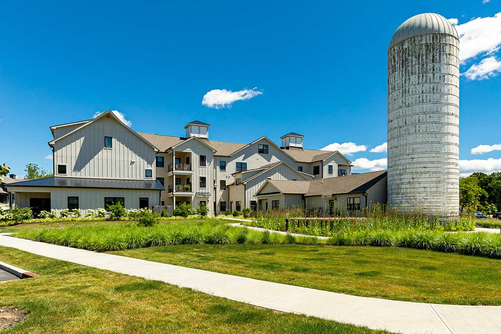 A large white building with a tall silo in front of it.