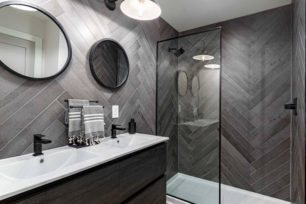 A bathroom with a sink, mirror, and shower.