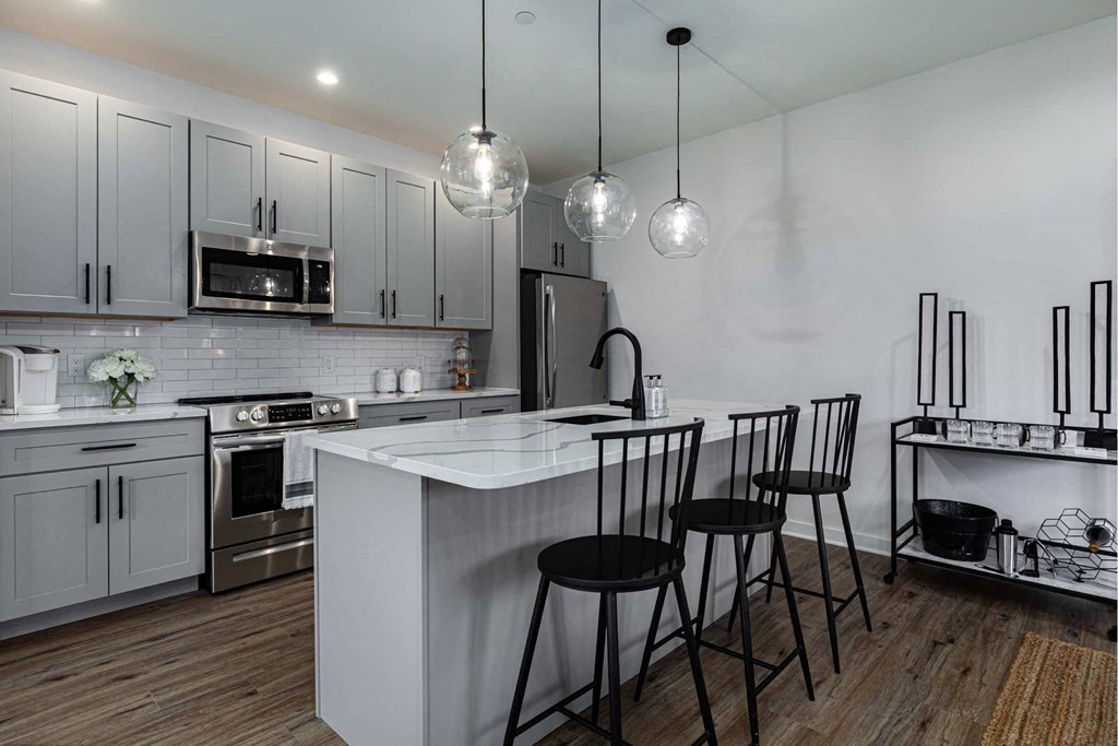 A modern kitchen with a white island and black bar stools.