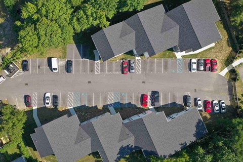 A parking lot with cars parked in rows in front of houses.