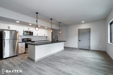 A modern kitchen with a stainless steel refrigerator and a white island.