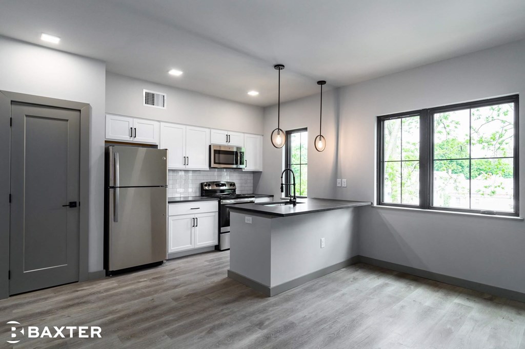 A modern kitchen with a refrigerator, microwave, and oven.