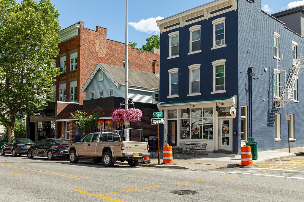 A street view with cars parked on the side of the road and buildings in the background.