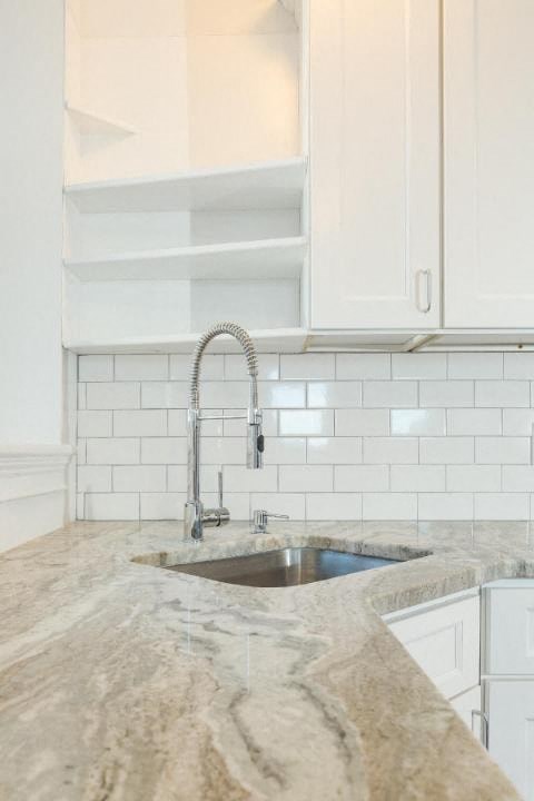 A kitchen with a sink and a marble countertop.