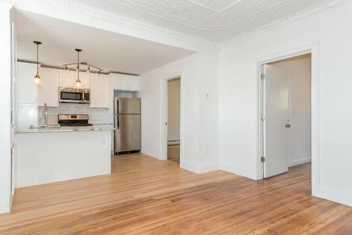 A kitchen with white cabinets and a wooden floor.