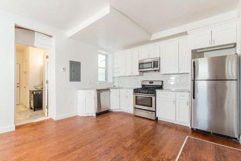 A kitchen with white cabinets and a wooden floor.