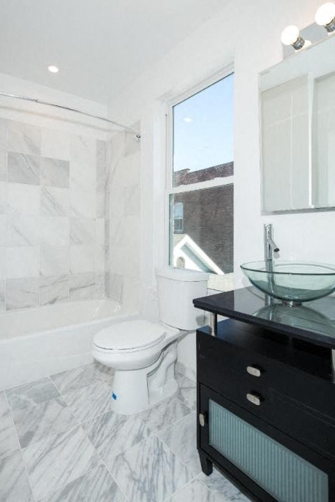A white toilet with a blue dot on the side is in a bathroom with a marble floor.