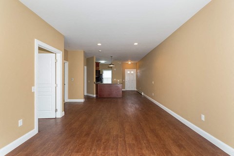 A long hallway with wood floors and white walls.