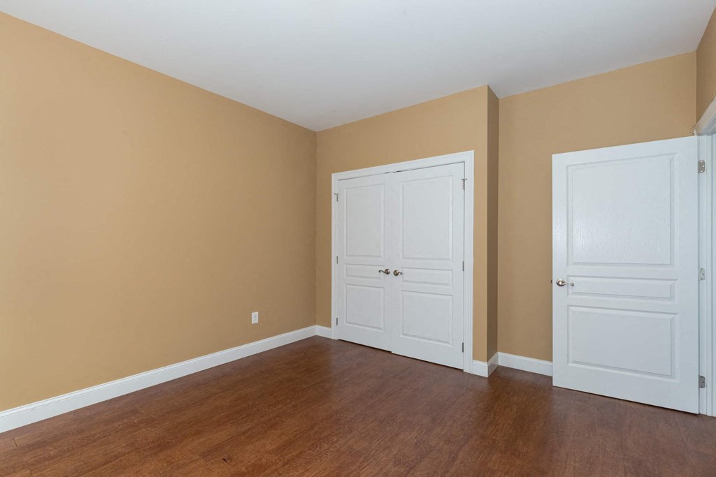 A room with two white doors and wooden floors.