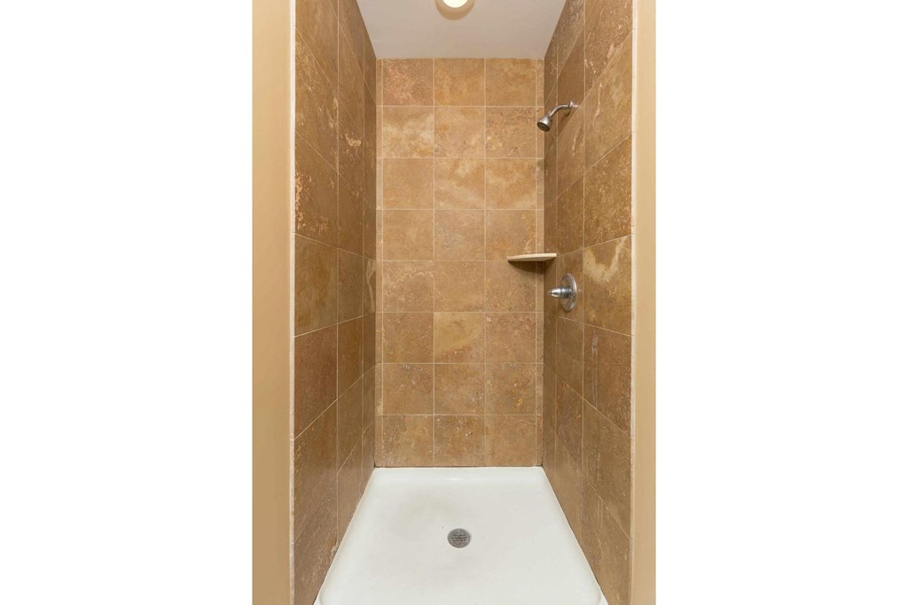 A shower area with a brown tile wall and a white floor.