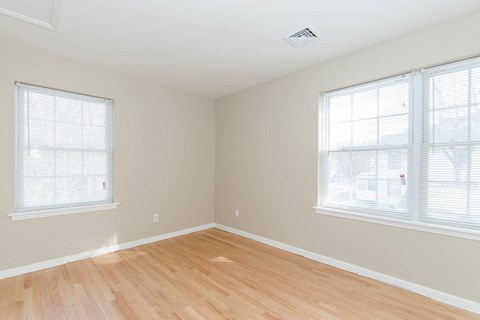 A room with wooden floors and two windows.