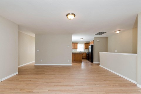 A spacious room with wooden floors and a kitchen area in the background.