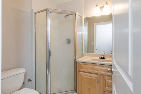 A white bathroom with a toilet, sink, and shower.