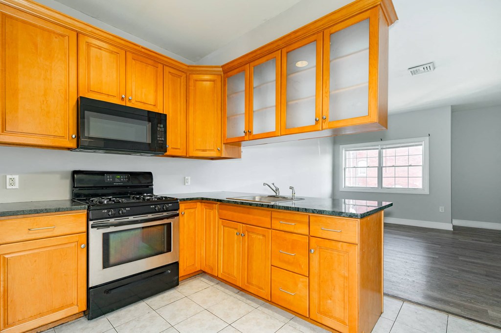 A kitchen with wooden cabinets and black appliances.