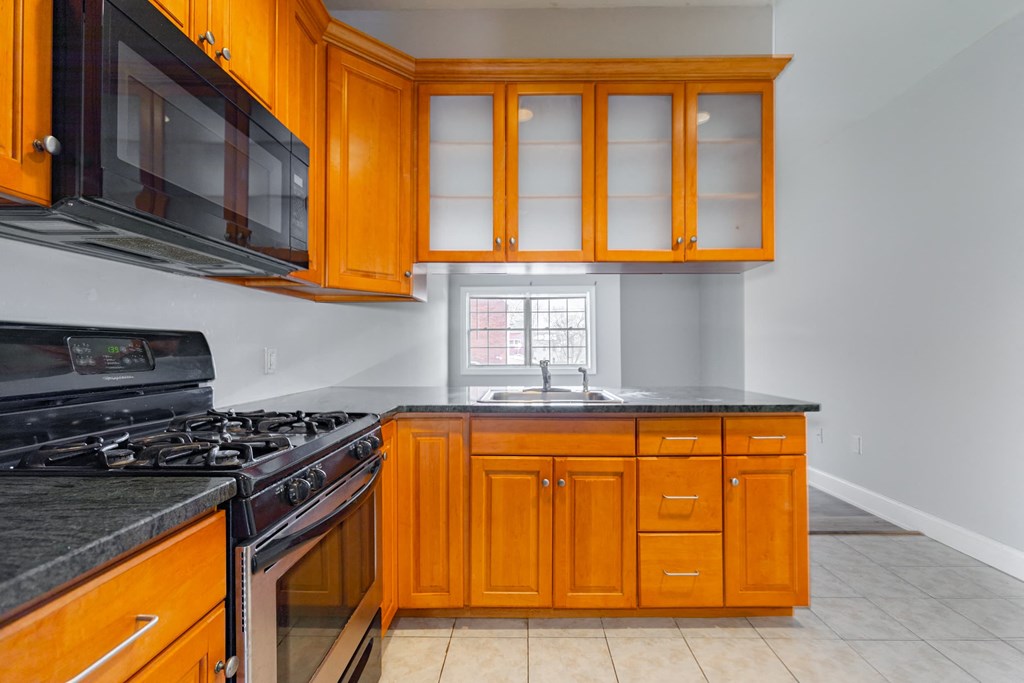 A kitchen with wooden cabinets and black appliances.