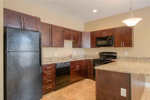 A kitchen with brown cabinets and a black refrigerator.