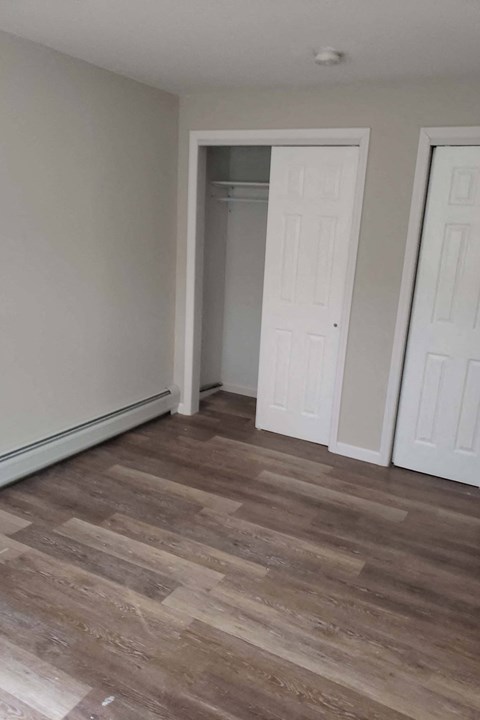 A room with a wooden floor and two white doors.