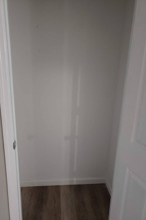 A white door is open to a room with a wooden floor.