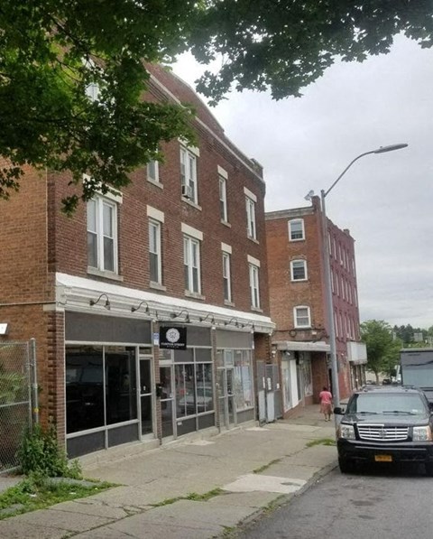 A street view of a brick building with a closed shop in front.