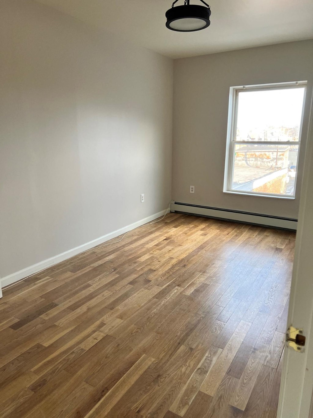 A room with a window and wooden flooring.
