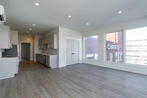 A spacious, empty room with light wood flooring and white walls.