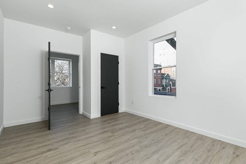 A room with a black door and a window with a view of a building outside.