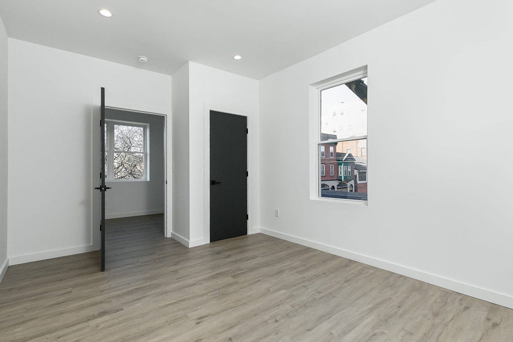 A room with a black door and a window with a view of a building outside.