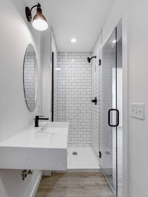 A white sink in a modern bathroom with a glass shower door.