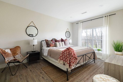 A bedroom with a bed, chair, and a rug.