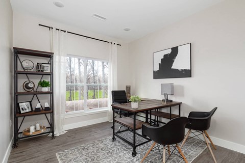 A black and white photo is hanging on a white wall above a wooden table.