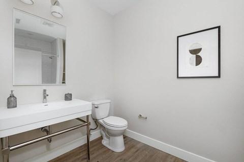 A bathroom with a toilet, sink, and mirror.