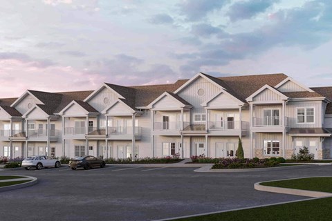 A row of townhouses with cars parked in front.