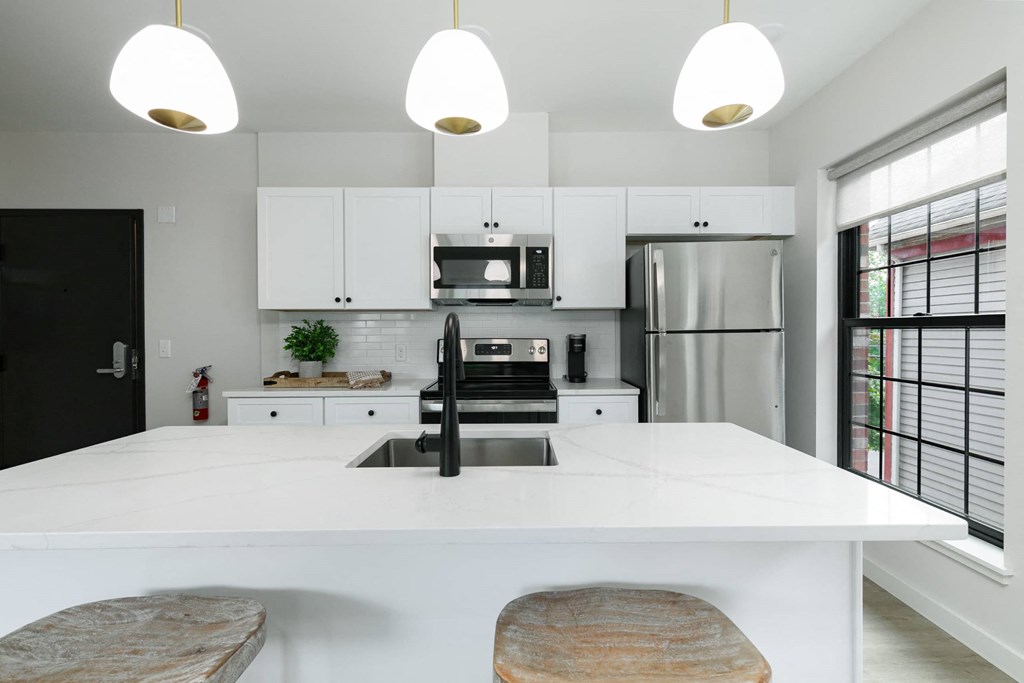 A modern kitchen with a white countertop and black appliances.
