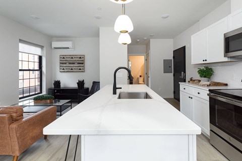 A modern kitchen with a white island and black appliances.