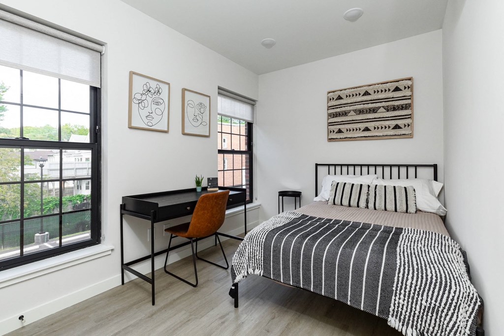 A bedroom with a bed, desk, and chair.