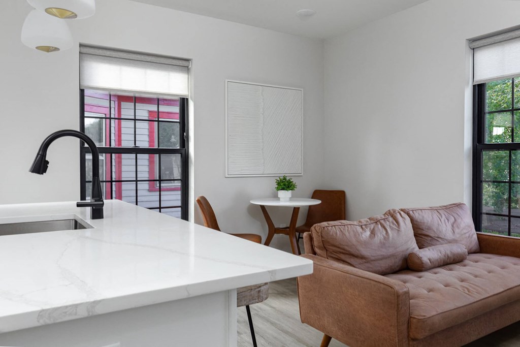 A kitchen with a marble countertop and a brown sofa.