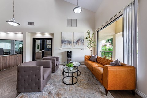 A living room with a brown couch and a glass table.