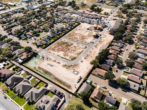 An aerial view of a neighborhood with a large empty lot in the center.