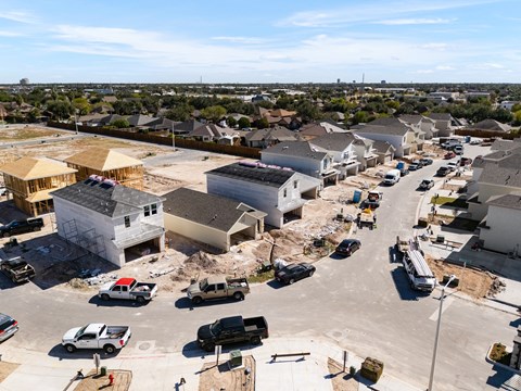 A construction site with multiple buildings under construction and vehicles parked around.