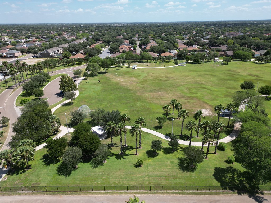 A large green field with trees and a road.