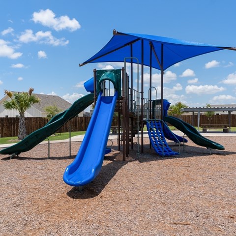A playground with a blue slide and a green slide.