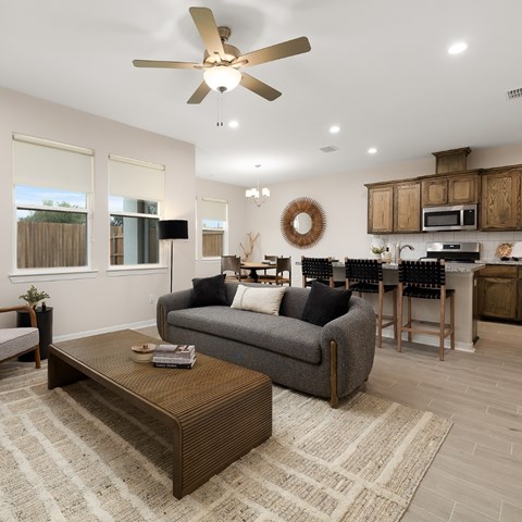 A living room with a grey couch, a coffee table, and a ceiling fan.