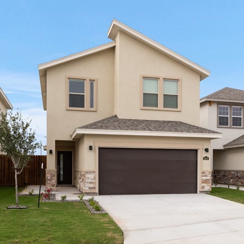 A beige house with a brown garage door and a stone pillar.