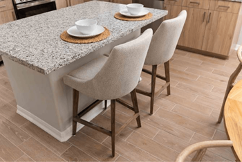 A kitchen with a granite countertop and chairs.