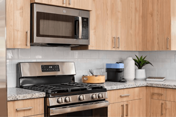A modern kitchen with a stove, microwave, and wooden cabinets.