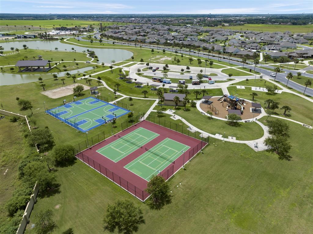 A tennis court is surrounded by a fence and a grassy area.