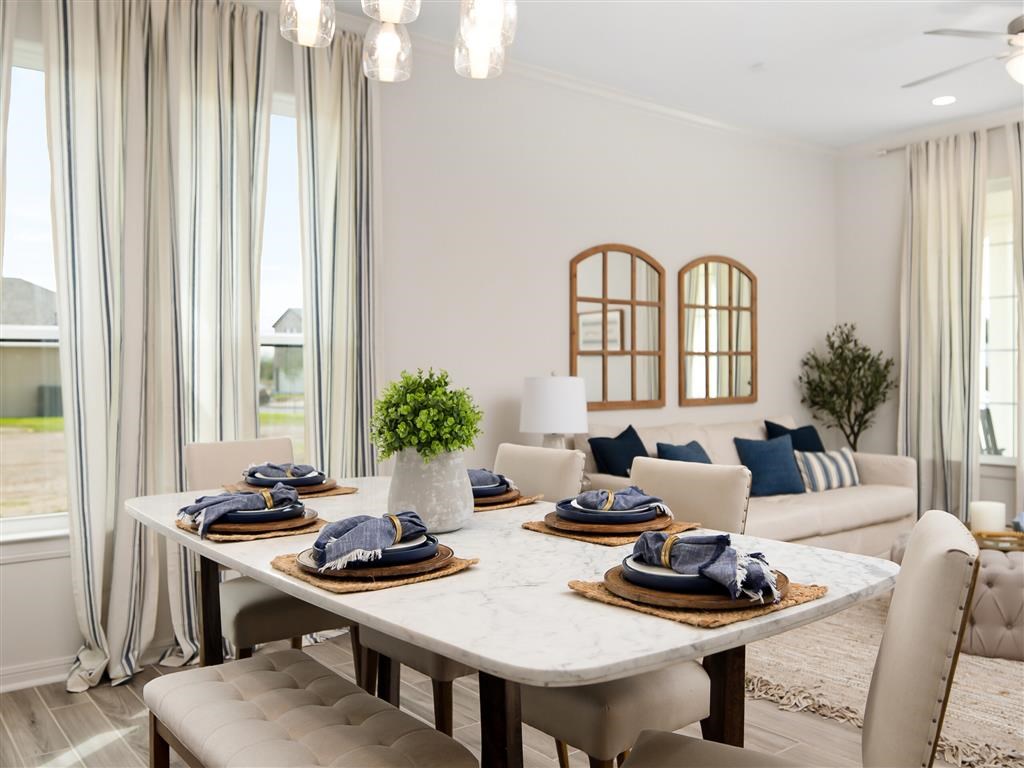 A dining room with a table set for two and a couch with blue pillows.